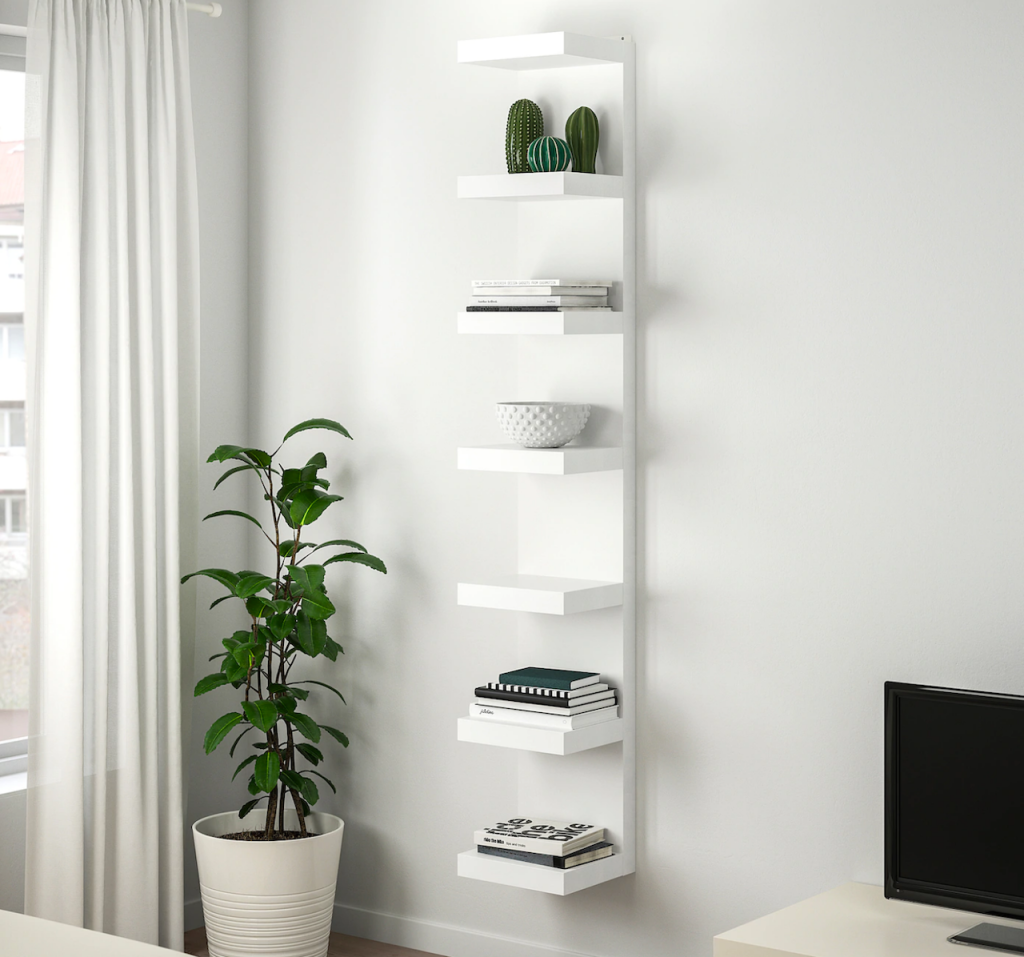 IKEA white wall unit with books and plant next to it